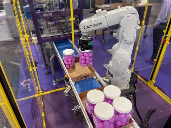 Pick and place robotic arm placing containers into cardboard trays