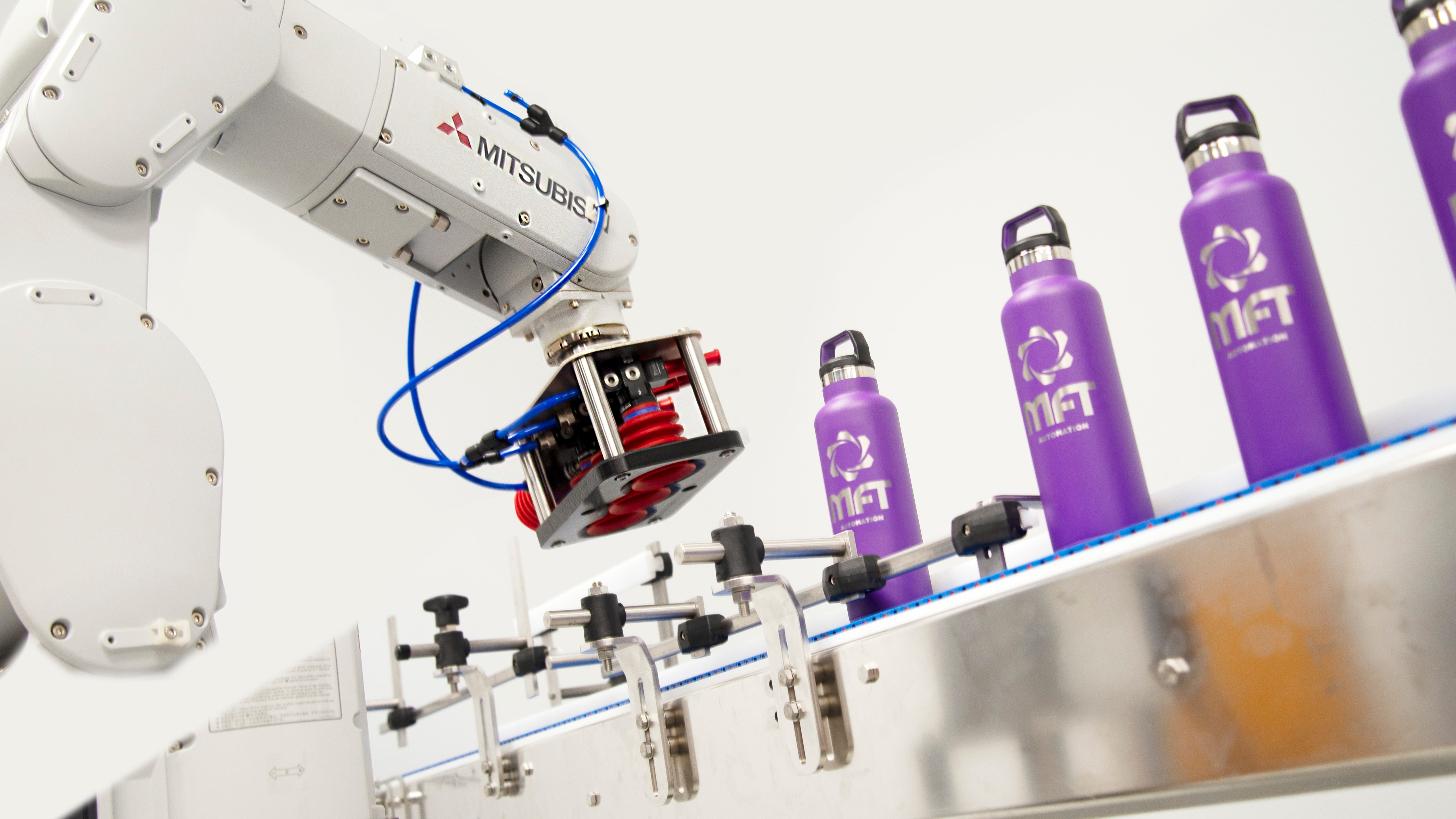 industrial robotic arm moving water bottles on a conveyor belt